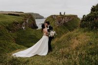 Bride holds a bouquet while kissing the groom above a mountain in Northern Ireland
